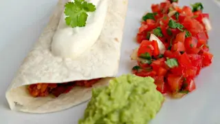 Na talerzu burrito z sosem, obok salsa i zielone, pyszne guacamole.