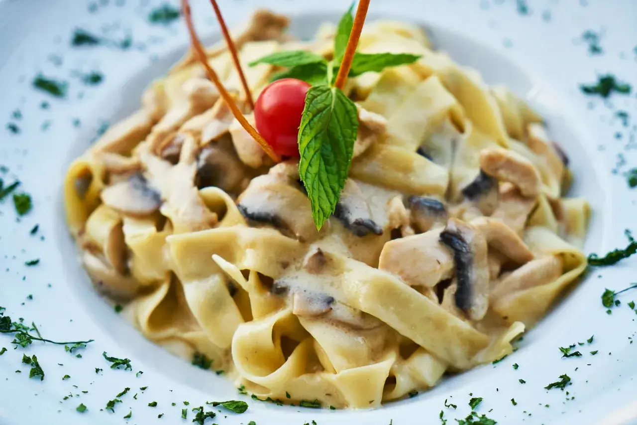 Tagliatelle z kurczakiem i grzybami w kremowym sosie. Idealny pomysł na to, jaki sos do makaronu z kurczakiem wybrać.