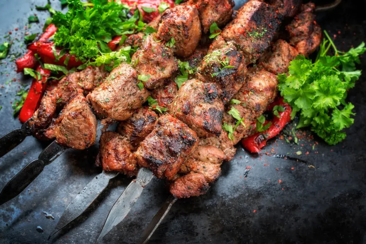 Chilli kebab na grillu, soczyste kawałki mięsa z przyprawami, podane z papryczkami i natką pietruszki.