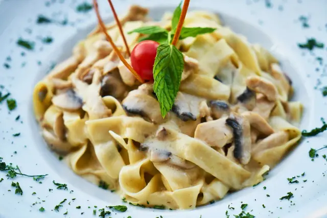 Tagliatelle z kurczakiem i grzybami w kremowym sosie. Idealny pomysł na to, jaki sos do makaronu z kurczakiem wybrać.
